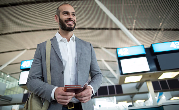 A man smiles confidently at the airport, ready to travel with help from immigration consultants in Kerala.